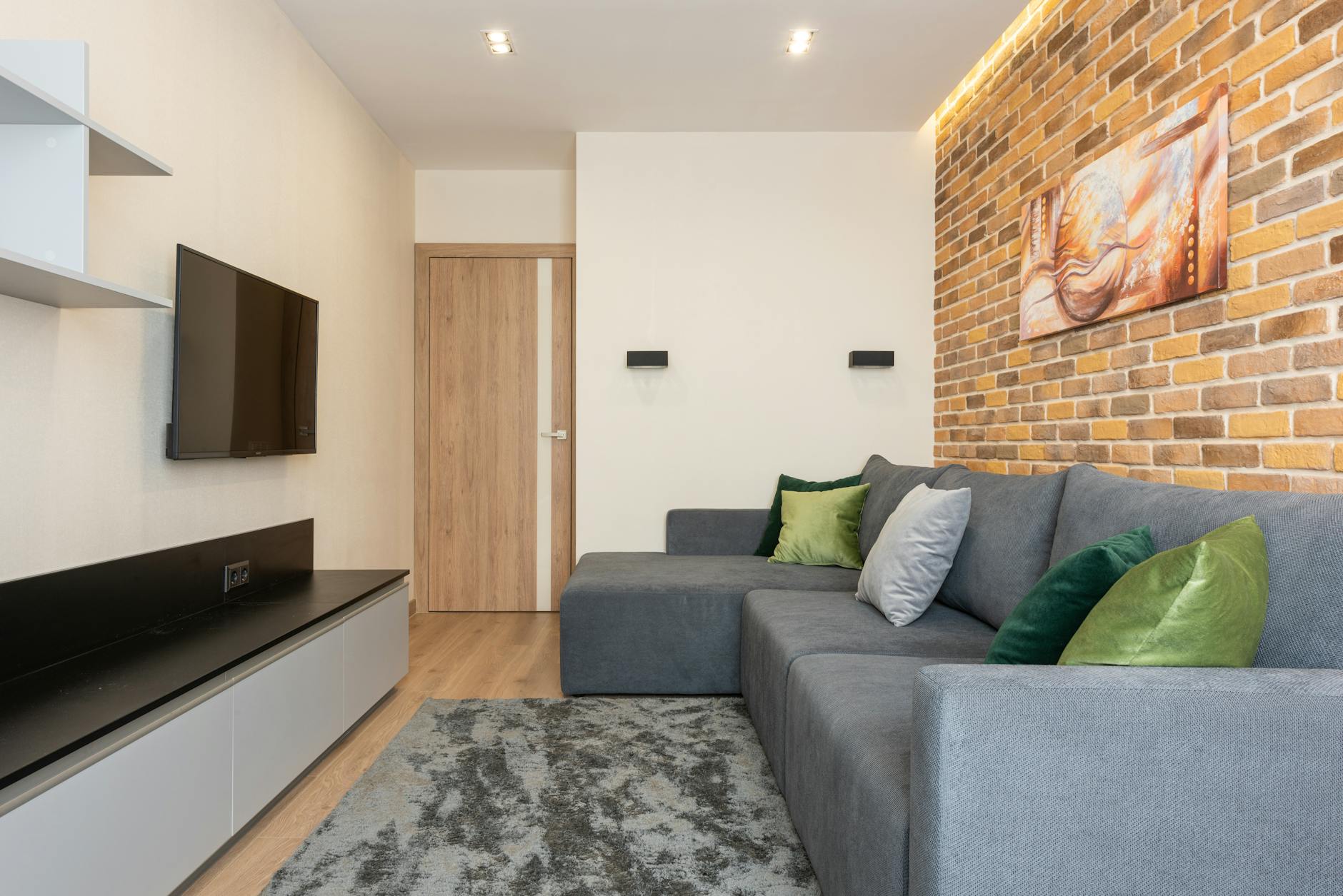 Przytulny nowoczesny salon z ceglaną ścianą i szarą kanapą