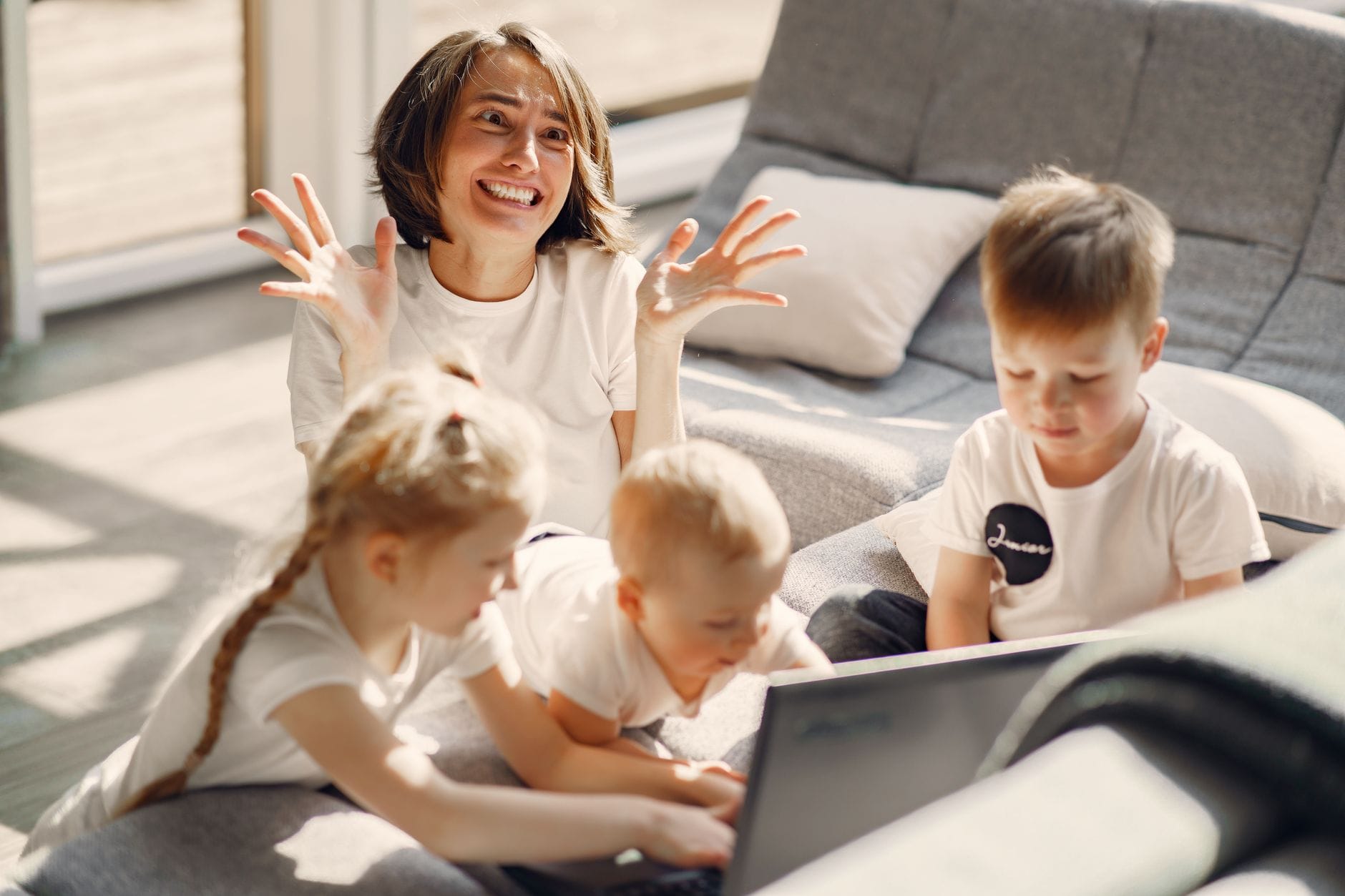 Zestresowana mama na kanapie, dzieci wpatrzone w laptop w salonie