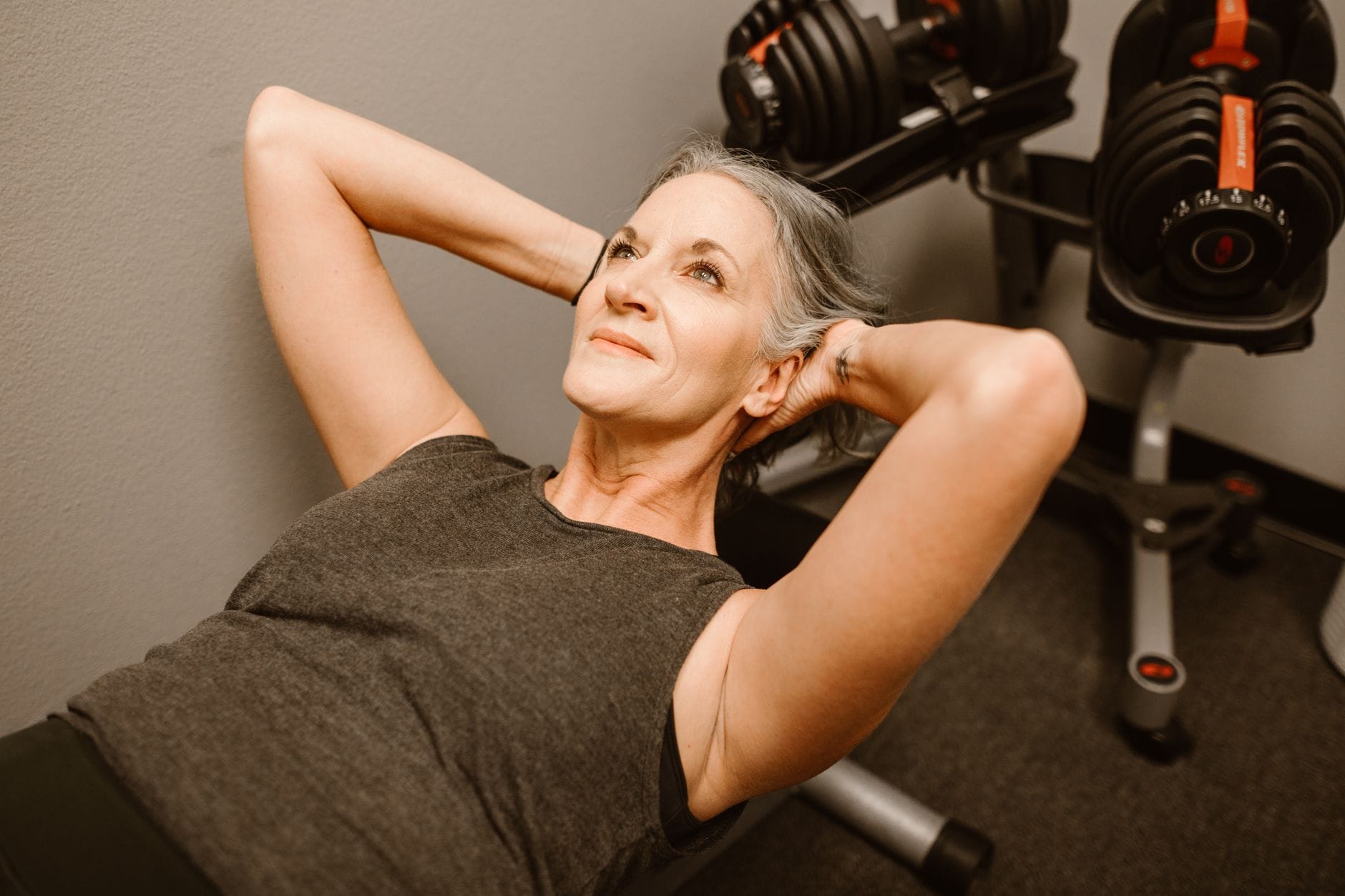 Seniorka ćwiczy z hantlami w nowoczesnym klubie fitness