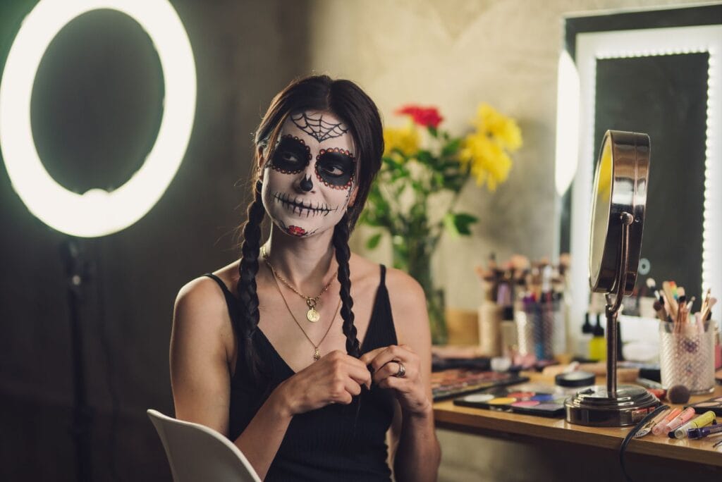 Kobieta z makijażem Catriny przygotowuje się do Día de los Muertos